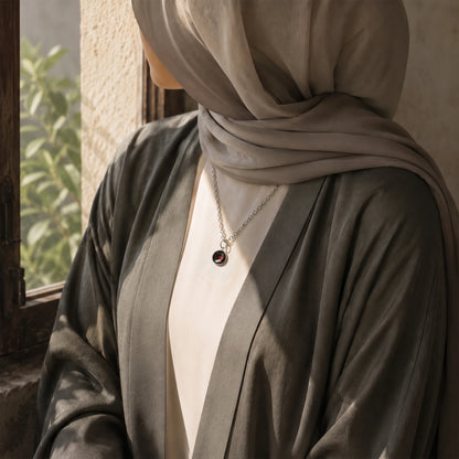 Model wearing a Dar Suad stainless steel necklace featuring one-of-a-kind artwork in black, red, and silver.