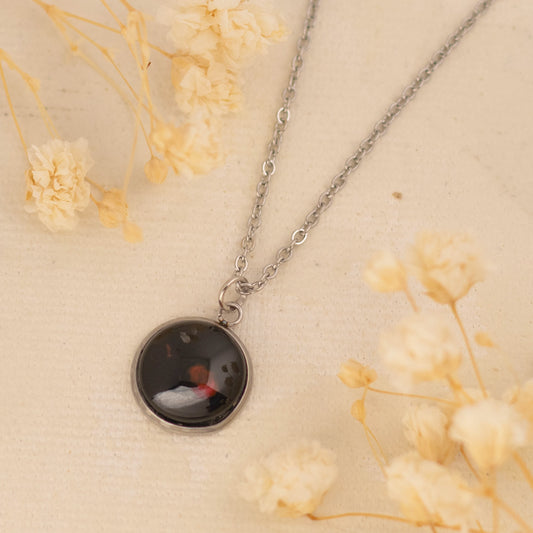 Dar Suad necklace featuring one-of-a-kind artwork in black, red, and silver with a stainless steel setting.