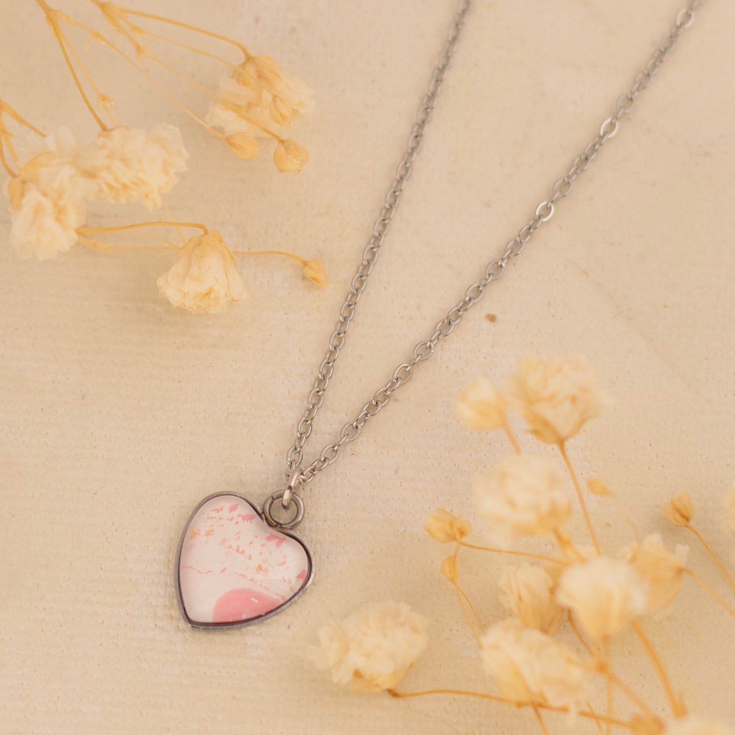 Dar Suad necklace featuring one-of-a-kind artwork in pink and white with a stainless steel setting.