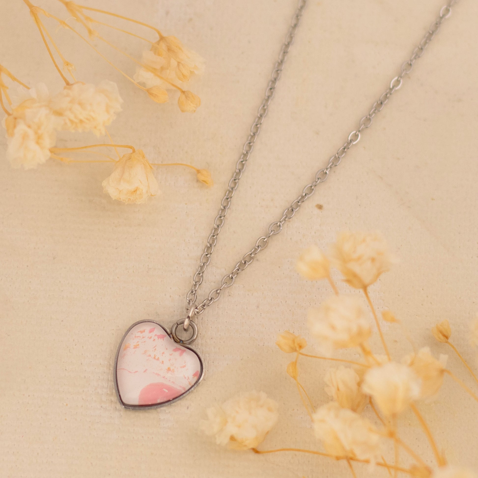 Dar Suad necklace featuring one-of-a-kind artwork in pink and white with a stainless steel setting.
