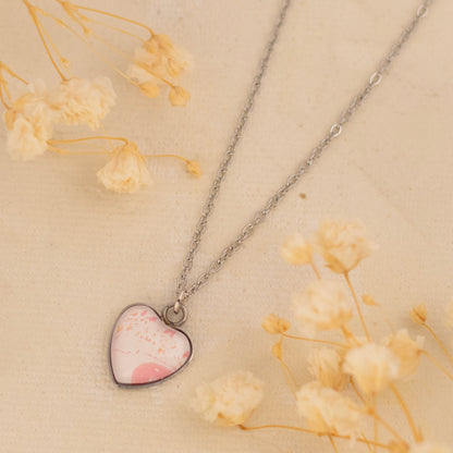 Dar Suad necklace featuring one-of-a-kind artwork in pink and white with a stainless steel setting.