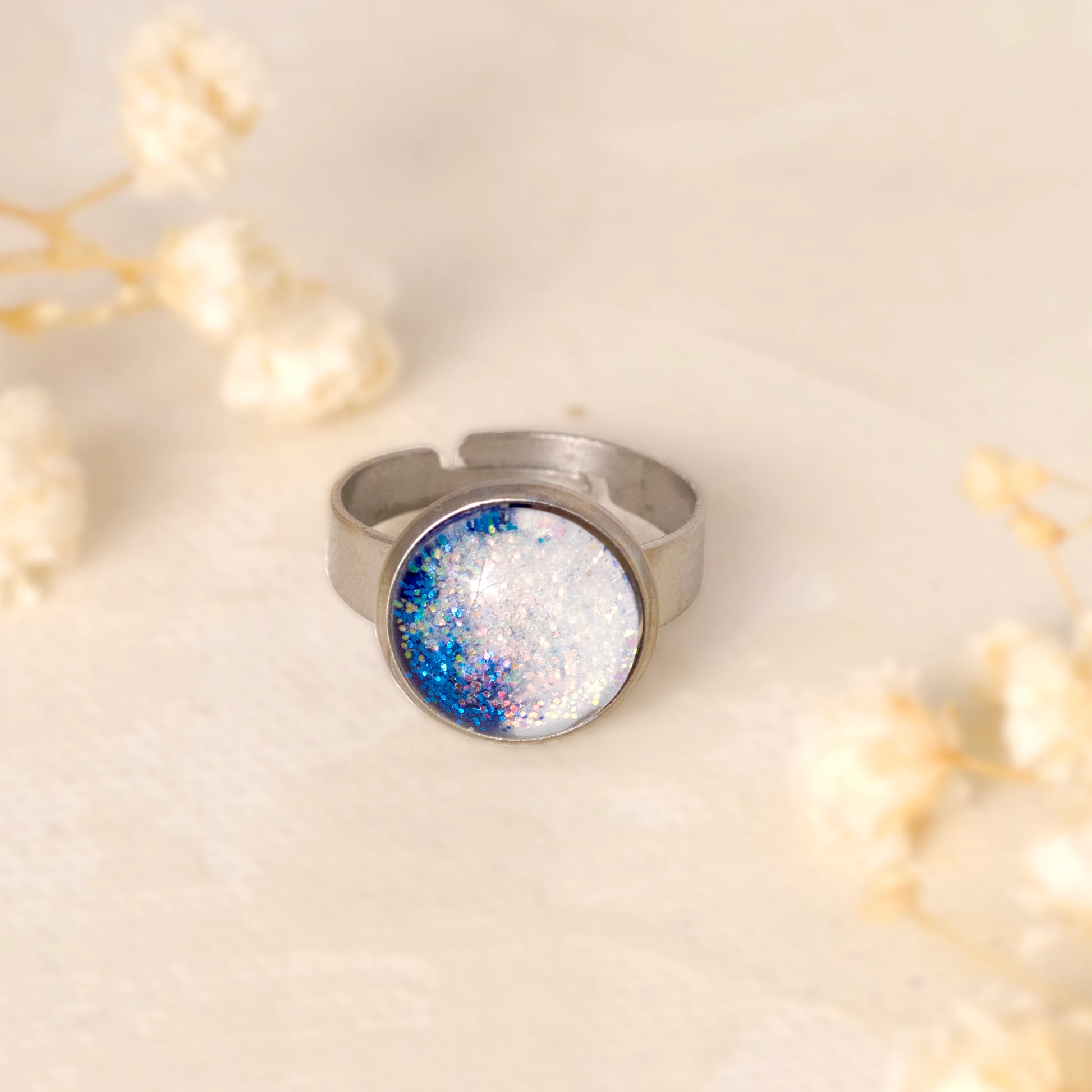 Dar Suad ring featuring one-of-a-kind original artwork in blue and white with a stainless steel setting.